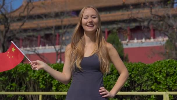 Slowmotion постріл жінка blogger, посміхаючись, проведення маленький прапор Китаю в руках. Поїздки в Китай концепції — стокове відео