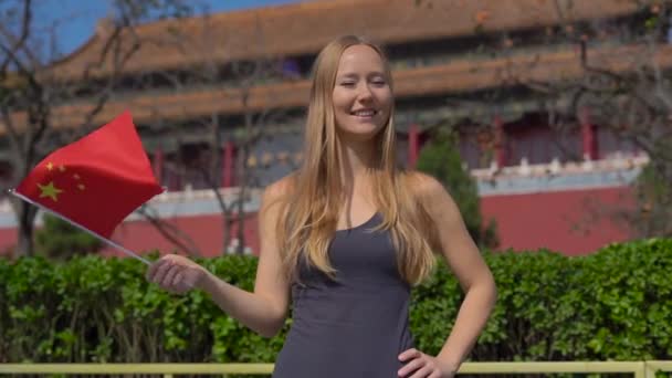 Zeitlupenaufnahme einer Bloggerin, die lächelnd eine kleine Porzellanfahne in den Händen hält. Reise nach China — Stockvideo