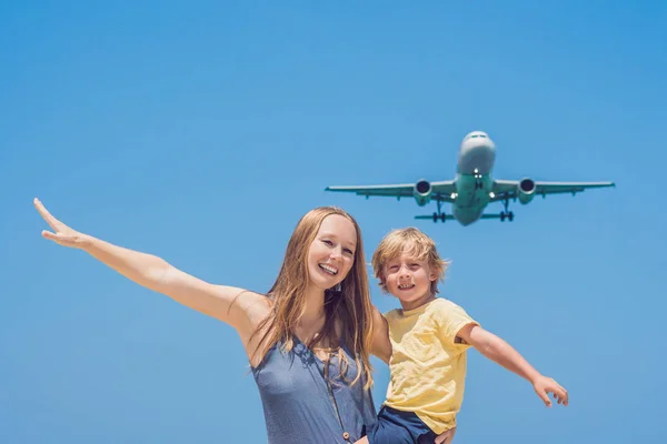 母と息子は、着陸飛行機を見てビーチで楽しい時を過します。子供たちのコンセプトと飛行機の旅 — ストック写真