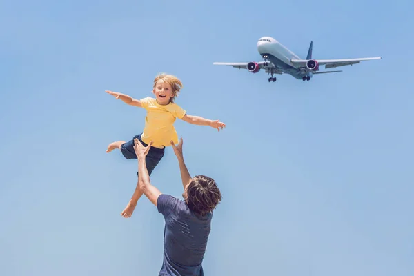 Padre e hijo se divierten en la playa viendo los aviones de aterrizaje. Viajar en un avión con concepto de niños — Foto de Stock