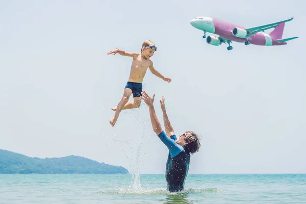 Padre e figlio si divertono sulla spiaggia a guardare gli aerei di atterraggio. Viaggiare su un aereo con concetto di bambini — Foto Stock