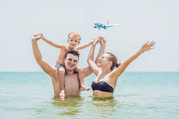 Famiglia felice sulla spiaggia e aereo atterraggio. Viaggiare con i bambini concetto — Foto Stock