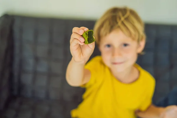 Un ragazzo che mangia caramelle Matcha verdi. Matcha fatto in casa — Foto Stock