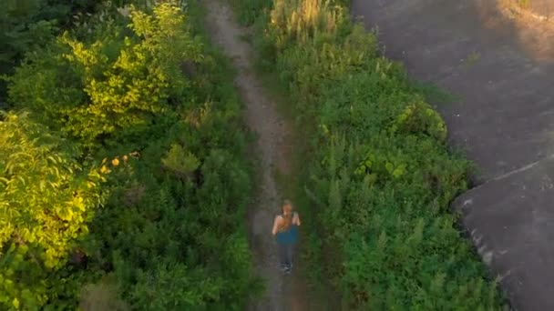 Foto aérea de una joven mujer corriendo en el territorio de una antigua fortaleza de la Primera Guerra Mundial al atardecer, al amanecer — Vídeos de Stock