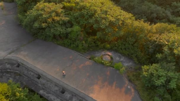 Tiro aéreo de uma jovem mulher correndo em cima de uma antiga fortaleza da Primeira Guerra Mundial durante o pôr do sol, nascer do sol — Vídeo de Stock