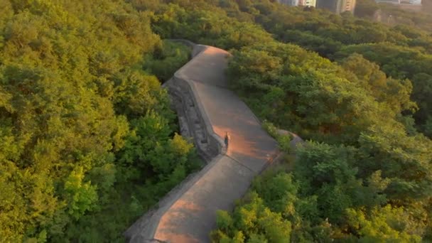 Foto aérea de una joven mujer corriendo sobre una antigua fortaleza de la Primera Guerra Mundial al atardecer, al amanecer — Vídeo de stock