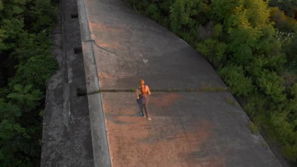 Plan aérien d'une jeune femme courant au-dessus d'une ancienne forteresse de la 1ère guerre mondiale au coucher du soleil, au lever du soleil — Video