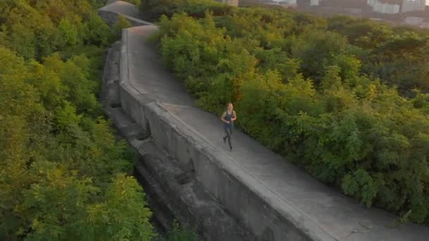 Foto aérea de una joven mujer corriendo sobre una antigua fortaleza de la Primera Guerra Mundial al atardecer, al amanecer — Vídeo de stock