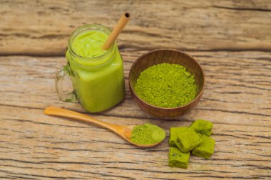 Ahşap arka plan matcha yeşil çay sütlü buz mason kavanoza, matcha tozu ve şeker ile yapılmış. Ev yapımı Matcha Latte çayları ile süt sıfır atık