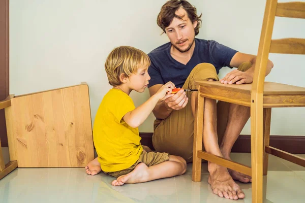 Padre e figlio assemblare mobili. Un ragazzo che aiuta suo padre a casa. Concetto famiglia felice — Foto Stock