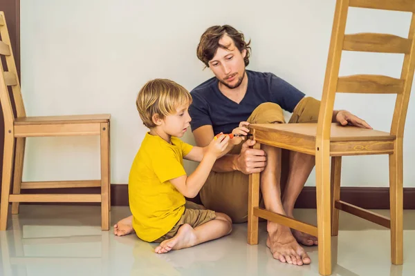 Pai e filho montando móveis. Rapaz a ajudar o pai em casa. Conceito de família feliz — Fotografia de Stock