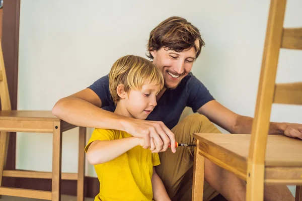 Padre e figlio assemblare mobili. Un ragazzo che aiuta suo padre a casa. Concetto famiglia felice — Foto Stock