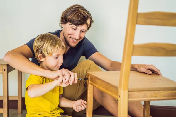 Padre e hijo ensamblando muebles. Un chico ayudando a su padre en casa. Concepto de familia feliz — Foto de Stock