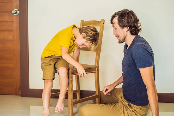 Pai e filho montando móveis. Rapaz a ajudar o pai em casa. Conceito de família feliz — Fotografia de Stock