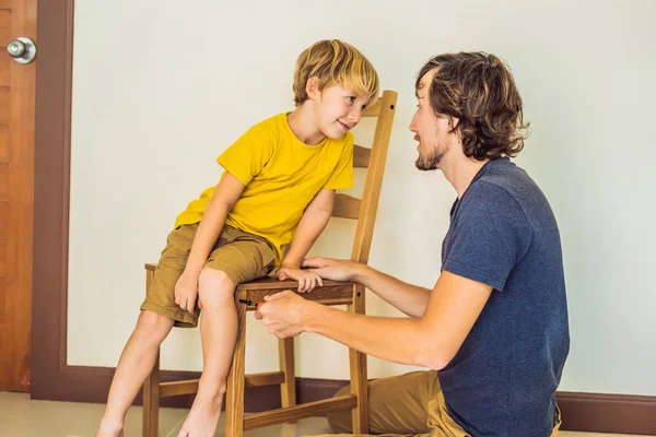 Far och son monterar ihop möbler. Pojken hjälper sin pappa hemma. Glad familj koncept — Stockfoto