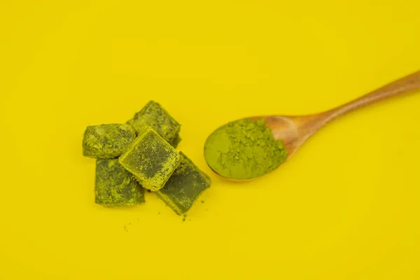 Cuchara con polvo de matcha y dulces de matcha sobre fondo amarillo. Matcha casera —  Fotos de Stock