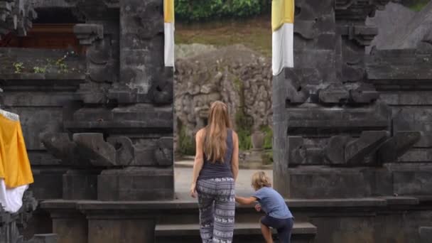 Filmagem em câmera lenta de uma jovem e seu filho visitando a Caverna dos Elefantes, Goa Gajah, na aldeia de Ubud, na ilha de Bali — Vídeo de Stock