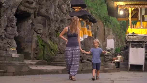 Νεαρή γυναίκα και τον μικρό γιο της επισκέπτονται το σπήλαιο ελεφάντων, Γκόα Gajah στο Ubud χωριό στο νησί Μπαλί — Αρχείο Βίντεο