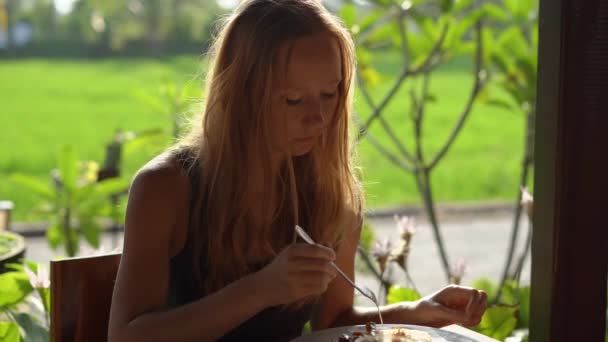 Primer plano de una joven cenando en un atardecer con un campo de arroz detrás de ella — Vídeos de Stock