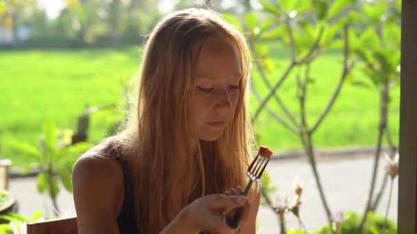Крупный план молодой женщины, обедающей на закате с рисовым полем за спиной — стоковое видео