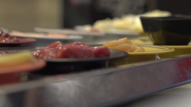 Transportador de comida. Café de estilo asiático com comida que se move em um transportador em pequenas placas. Conceito de desperdício de alimentos. desperdiçar Conceito de comer demais — Vídeo de Stock