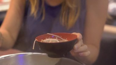 Genç kadın bir Asya kafe aşçı gıda bir güveç içinde. Yiyecek bir konveyör küçük tabaklarda servis edilir. Gıda konveyör.