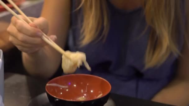 Junge Frau in einem asiatischen Café kocht Essen in einem heißen Topf. Das Essen wird auf einem Band auf einem kleinen Teller serviert. Lebensmittelförderer. — Stockvideo