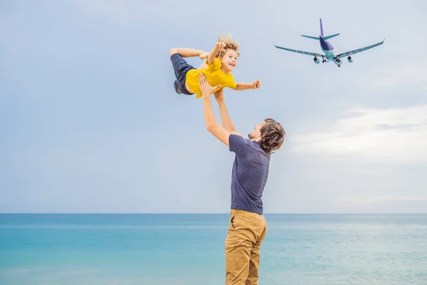 Padre e figlio si divertono sulla spiaggia a guardare gli aerei di atterraggio. Viaggiare su un aereo con concetto di bambini — Foto Stock