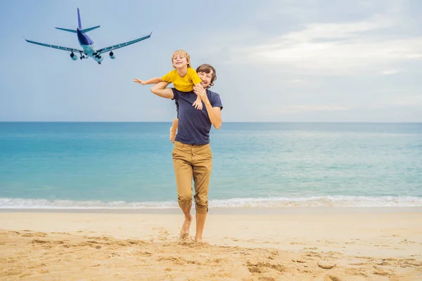 Padre e figlio si divertono sulla spiaggia a guardare gli aerei di atterraggio. Viaggiare su un aereo con concetto di bambini — Foto Stock