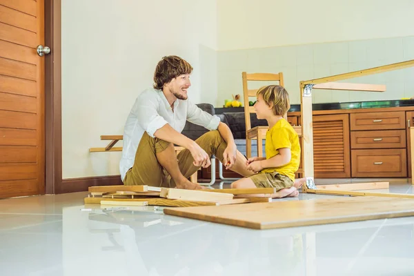 Padre e figlio assemblare mobili. Un ragazzo che aiuta suo padre a casa. Concetto famiglia felice — Foto Stock
