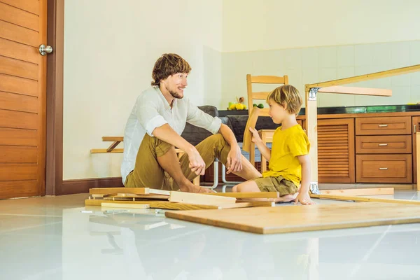 Ojciec i syn montują meble. Chłopiec pomaga ojcu w domu. Koncepcja Happy Family — Zdjęcie stockowe