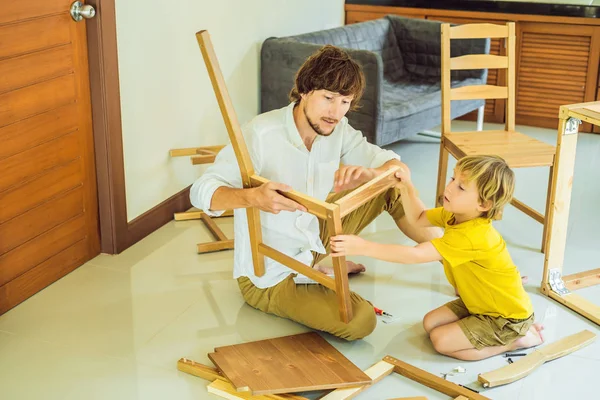 Padre e hijo ensamblando muebles. Un chico ayudando a su padre en casa. Concepto de familia feliz — Foto de Stock