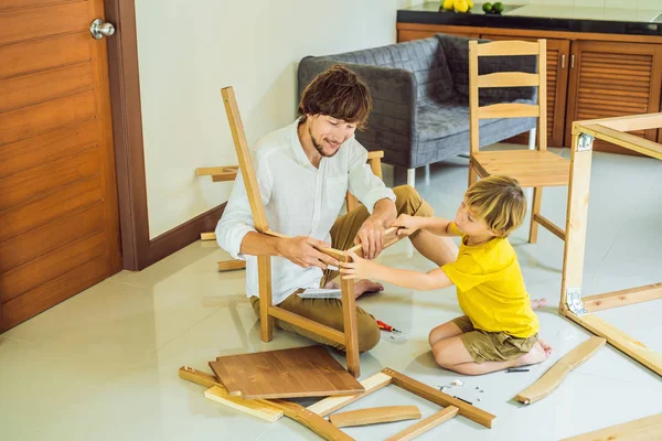 Padre e hijo ensamblando muebles. Un chico ayudando a su padre en casa. Concepto de familia feliz — Foto de Stock