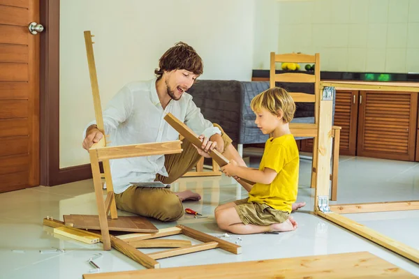 Padre e hijo ensamblando muebles. Un chico ayudando a su padre en casa. Concepto de familia feliz — Foto de Stock