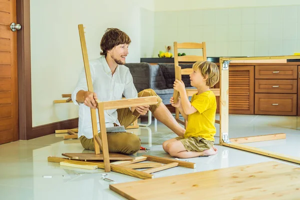 Padre e hijo ensamblando muebles. Un chico ayudando a su padre en casa. Concepto de familia feliz — Foto de Stock