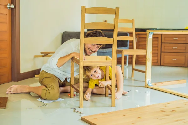 Far och son monterar ihop möbler. Pojken hjälper sin pappa hemma. Glad familj koncept — Stockfoto
