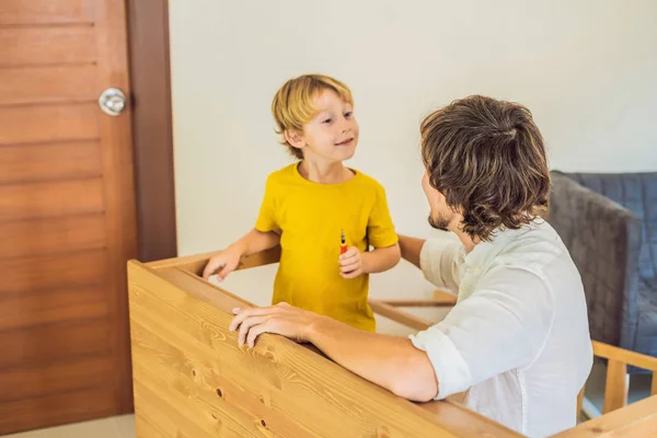 父亲和儿子组装家具。男孩帮助他的爸爸在家里。快乐家庭概念 — 图库照片