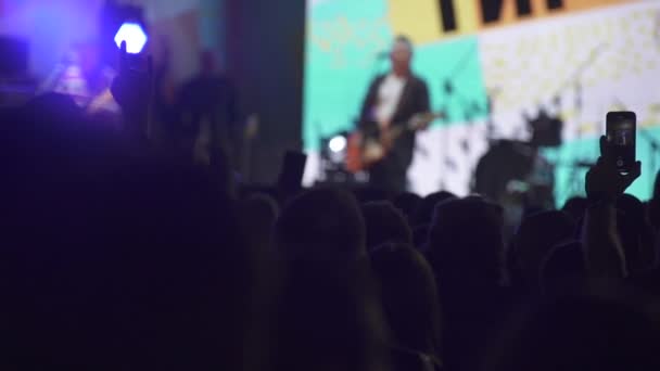 Slowmotion tiro de silhuetas de pessoas em uma multidão no fundo do palco em um concerto — Vídeo de Stock