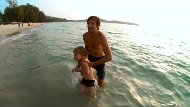 Superslowmotion skott av en far som kastar sin son i havet — Stockvideo