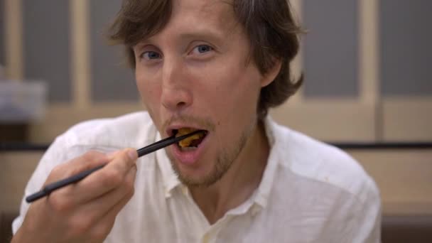 Slowmotion shot of a young man eatimg asian food in japanese-korean cafe — Stock Video