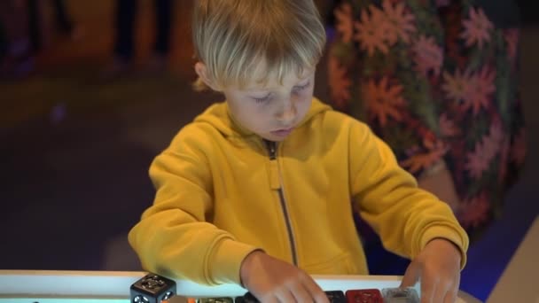 Уповільнений знімок маленького хлопчика, який відвідує музей науки для дітей. Він грає з модульним роботом — стокове відео