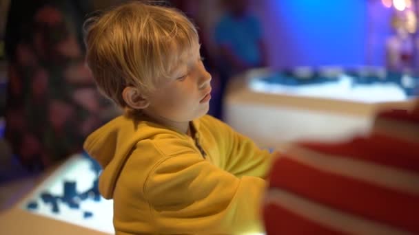 Slowmotion skott av en liten pojke på besök ett science museum för barn. Han spelar med en modulär robot — Stockvideo