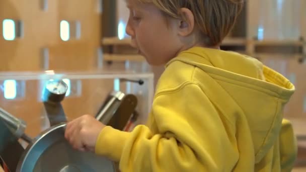 Kleiner Junge besucht ein naturwissenschaftliches Museum für Kinder. er komprimiert Luft mit einer Handpumpe, um eine Plastikflasche nach oben fliegen zu lassen — Stockvideo