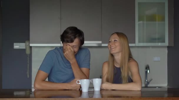 Молодая пара мужчин и женщин на кухне веселятся и смеются — стоковое видео