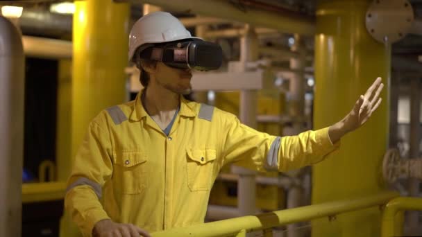 Joven en uniforme de trabajo amarillo en ambiente industrial, plataforma petrolera o planta de gas licuado utiliza gafas VR. Disparo en cámara lenta — Vídeos de Stock