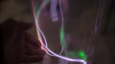 Yükleme bir Bilim Müzesi'nde. Bir kadın tauching ile parlayan gaz tüp bir el Slowmotion vurdu. inert gaz ışık emisyon. parlayan bir plazma ile tüp