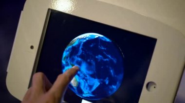 Ağır çekim bir tablet dokunur ve model bir dünya'nın yörünge bir adam bir kadeh. Astronomi buluşması