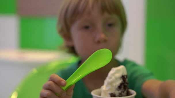 Closeup shot of a little boy eating delicious frozen yogurt icecream — Stock Video