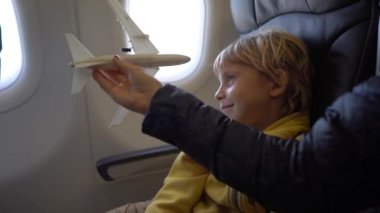 Bir sandalyede bir uçağın onboard oturan beyaz oyuncak uçak ile oynayan küçük bir çocuk Slowmotion vurdu. Özgürlük kavramı. Çocukluk kavramı. Çocuklar seyahat kavramı