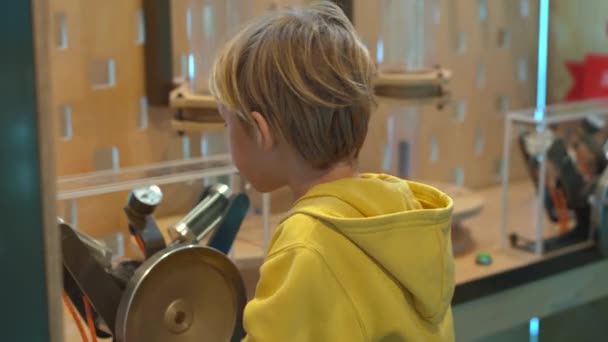 Little boy visits a science museum for children. He compresses air with a hand pump in order to make a plastic bottle fly up — Stock Video